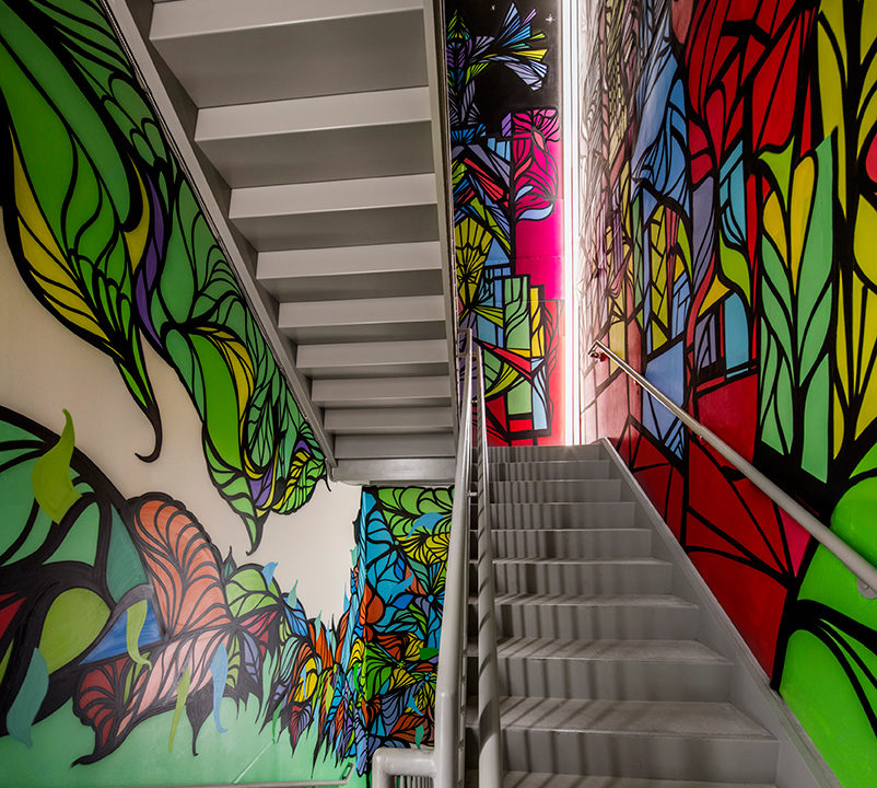 A stairwell with green, pink, red, and blue designs on the wall