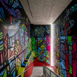 A stairwell with green, pink, red, and blue designs on the wall
