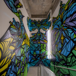 A stairwell with green, blue, and yellow designs on the wall