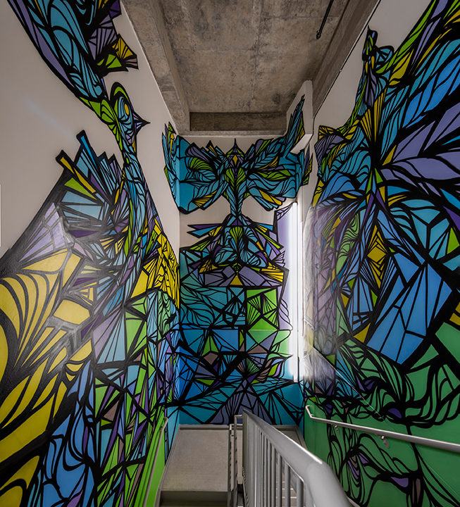 A stairwell with green, blue, and yellow designs on the wall