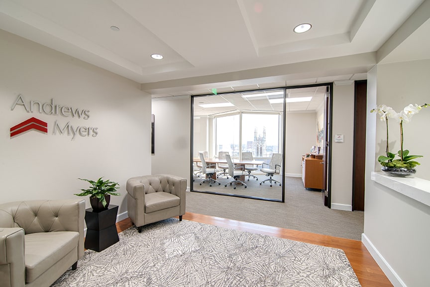 An office with beige leather chairs and a window opening to a conference room. There is an Andrews Myers sign on the wall