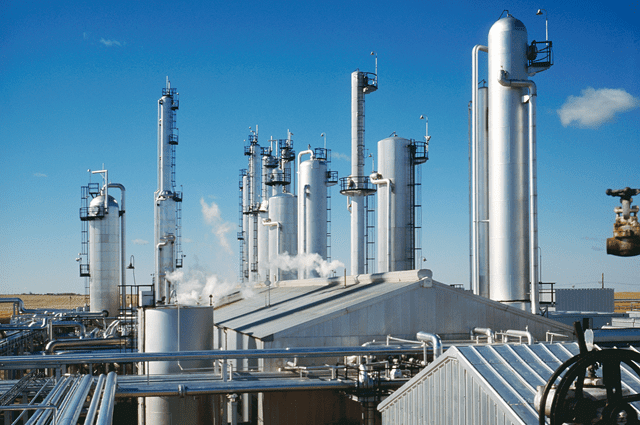 A chemical plant with large silver cylinders emitting smoke