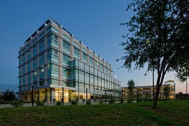 A large glass building with floor to ceiling windows and a grass lawn in front